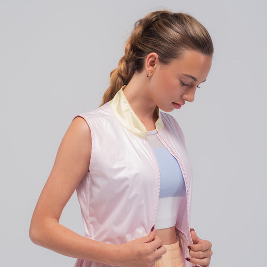 Imagen lateral con detalle de cremallera de chaleco de running rosa con cuello amarillo